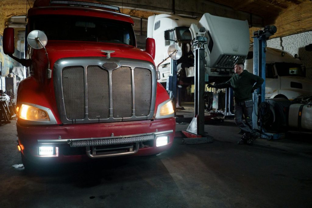 Roter LKW und Mechaniker in Werkstatt, deutet auf Wartung vor dem Verkauf hin.