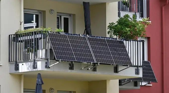 Mehrere Solarmodule an Balkongeländern eines Wohnhauses