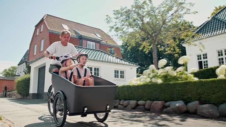 Familie fährt gemeinsam mit einem Lastenrad durch ein Wohnviertel
